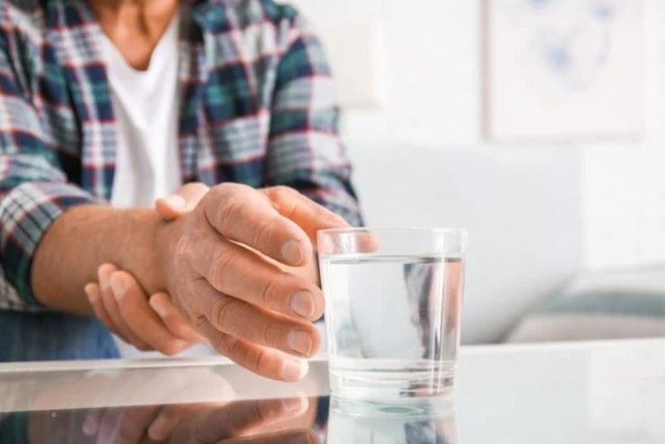Persona con camisa a cuadros y vaso de agua